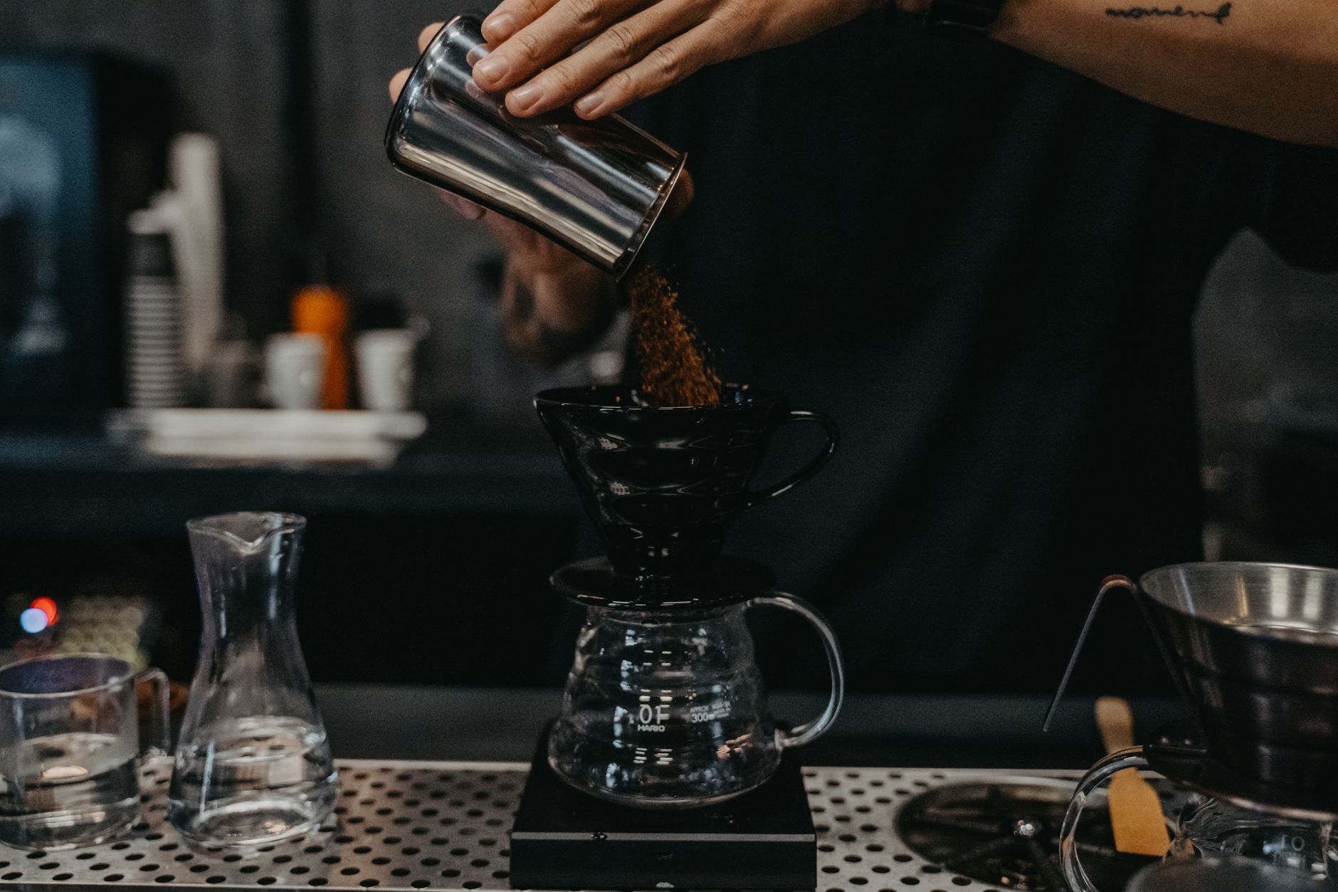 Barista sirviendo café de olla en la barra de la cafetería con luz de la mañana